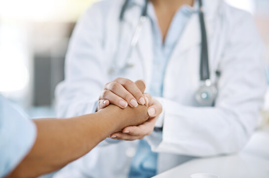 Woman, doctor and holding hands with patient for consultation, sympathy or comfort at hospital. Closeup, female person or medical professional with touch for grief, news or empathy at clinic visit