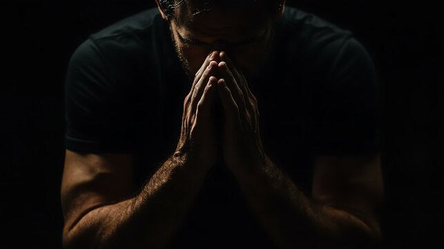 God, worship and man with hands praying for help, hope and guidance in dark studio. Pray, thank you and Christian male in prayer for hope, gratitude and holy praise, faith or blessing to Jesus