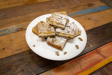 A delicious plate of Apple Crumble Cheesecake Square Bars on a wooden kitchen table