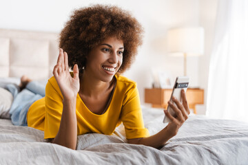 Happy African American woman waving by hands using mobile phone talking online