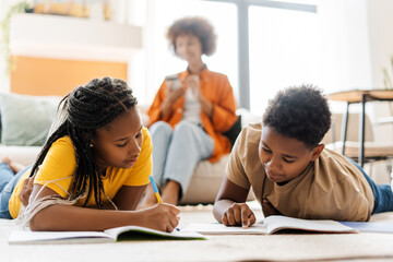 Woman holding mobile phone, sitting on sofa, little daughter and son drawing