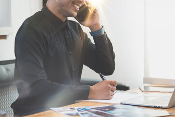 Smiling mature businessman holding smartphone sitting in office. Middle aged manager ceo using cell phone mobile apps and laptop. Digital technology applications and solutions for business development