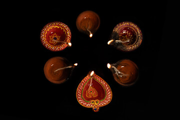 Top view of Diwali oil lamps lit during on black background.