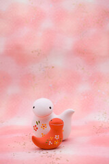 ピンク柄の背景に紅白の蛇の置き物　巳年　年賀素材　