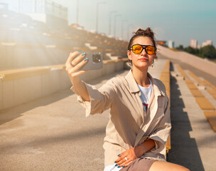 Young beautiful hipster woman taking selfie with smartphone on the street.