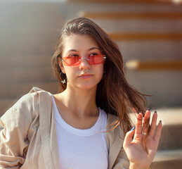 Portrait of a beautiful young girl in sunglasses on the background of stairs