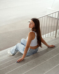 Portrait of a beautiful young woman sitting on the stairs outdoors.
