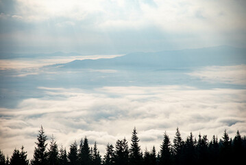 Obraz premium Majestic Mountain Landscape Covered in Mist with Sun Rays Breaking Through Clouds