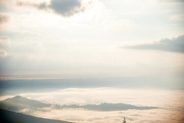 Majestic Mountain Landscape Covered in Mist with Sun Rays Breaking Through Clouds
