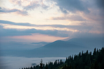 Majestic Mountain Landscape Covered in Mist with Sun Rays Breaking Through Clouds
