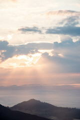 Majestic Mountain Landscape Covered in Mist with Sun Rays Breaking Through Clouds