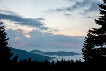 Majestic Mountain Landscape Covered in Mist with Sun Rays Breaking Through Clouds