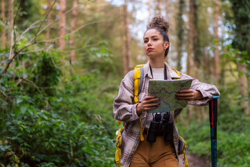 The curly-haired beauty takes a break on the forest trail, checking her map to navigate the serene autumn surroundings.