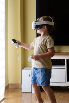 Excited child with virtual reality glasses in the living room at home. School education program for children. Surprised little boy looking with VR glasses