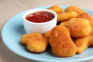 Tasty chicken nuggets with chili sauce on table, closeup