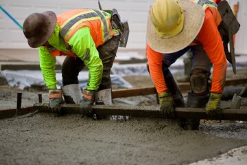road crew spreading the wet concrete evenly