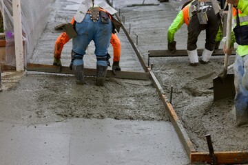 road crew spreading wet concrete evenly