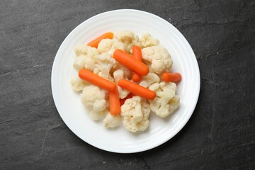 Tasty cauliflower with baby carrots on black table, top view