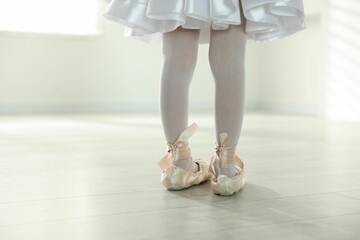 Little ballerina wearing pointe shoes indoors, closeup