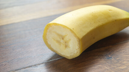 A piece of banana cut in half on a wooden table close-up