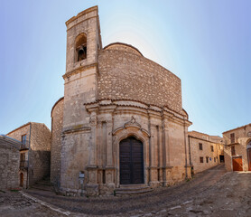 Church of Most Holy Saviour in Petralia Soprana, Sicily. Historic stone church, tall bell tower and ornate arched doorway. Rounded structure, architectural details reflect centuries of craftsmanship