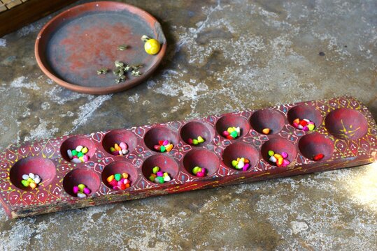 Dakon or congklak or mancala game board with colorful seed in the hole. Traditional Javanese game