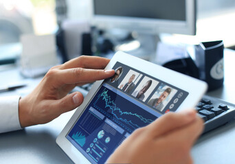 Close up of person video conferencing with colleagues on digital tablet, analyzing financial statistics displayed on the digital tablet screen