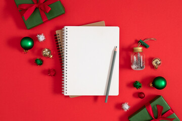 Christmas concept. Xmas checklist or invitation on red table. Blank notebook with pencil and...