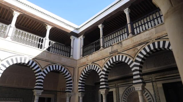 Traditional Tunisian courtyard with intricate arches and striped patterns under a bright blue sky