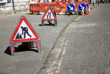 paved street with road signs on road works and road narrowing