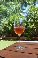 Glass of rose wine on wooden table outdoor
