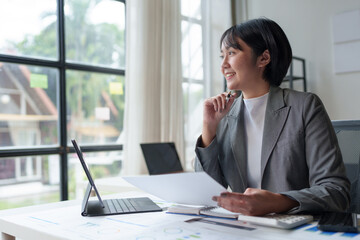 Fototapeta premium Asian woman doing finance business analyzing paperwork, growth, online market research report and statistics financial and accounting concept, analysis.