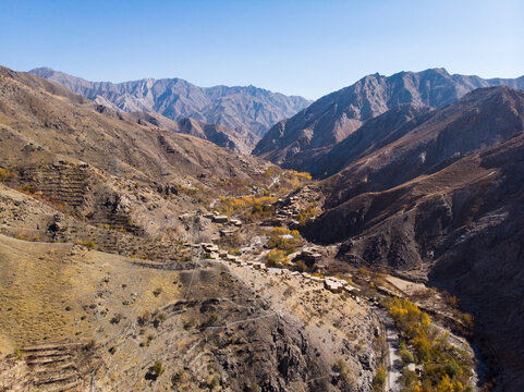 Aerial view of majestic mountains surrounding a tranquil valley with a remote village, Salang, Afghanistan.