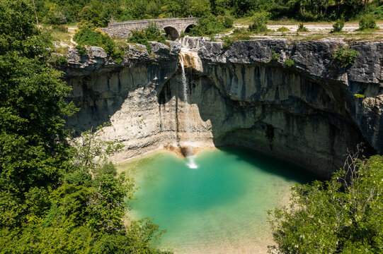 Aerial view of a breathtaking cascading waterfall in a lush green canyon surrounded by rugged cliffs and serene forest, Pican, Croatia.