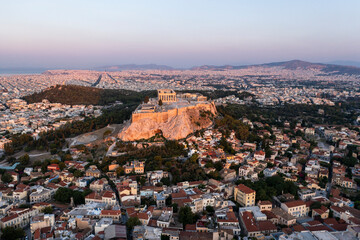 Aerial view of the historic acropolis with beautiful ancient ruins and cityscape at sunset, Athens, Greece.