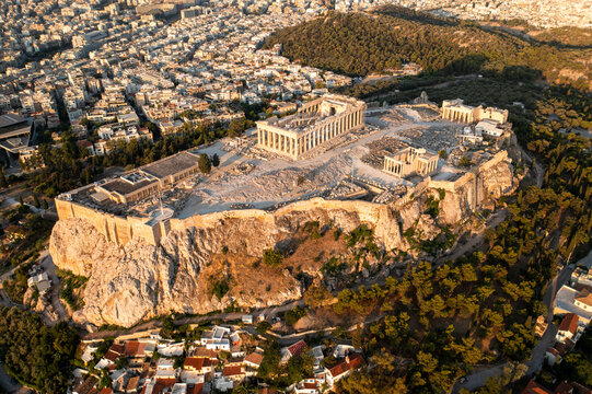 Aerial view of the historic acropolis with the parthenon and ancient ruins surrounded by a beautiful cityscape and trees, Athens, Greece.