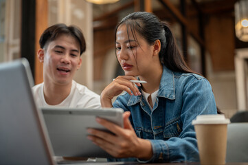 A beautiful Asian woman is focusing on listening to her male colleague explaining his idea.