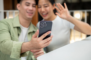 A man holding a phone to take a selfie with his girlfriend while they hang out together at a cafe.