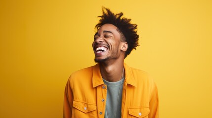 Fototapeta premium A joyful young man in a bright yellow jacket laughs heartily against a vibrant yellow backdrop, exuding a mood of pure happiness and positivity.