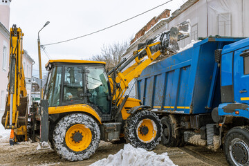A yellow and blue construction vehicle is pulling a blue dump truck