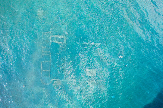 Aerial view of underwater ruins in turquoise water, Archea Epidavros, Greece.