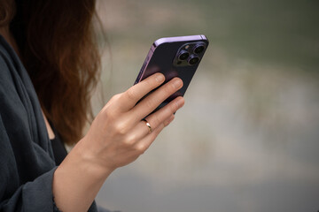 A woman is sitting on a dock with a laptop and a cell phone. She is talking on the cell phone while...