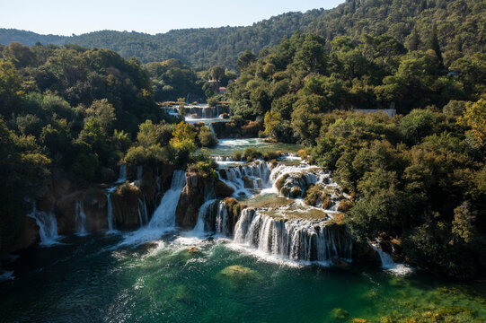 Aerial view of skradinski buk waterfall cascading through a scenic forest and turquoise river, Skradin, Croatia.