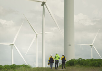  engineering technicians supervise wind power wind turbines during a sunny and windy day. Renewable...