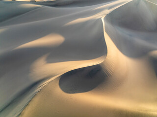Aerial view of beautiful sand dunes in a serene desert landscape under golden sunlight, Stovepipe Wells, United States.