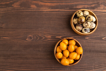Pile of smoked quail eggs in bowl on a brown wooden background. top view, copy space.