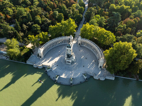 Aerial view of tranquil Retiro Park with a beautiful monument and serene water reflections, Madrid, Spain.