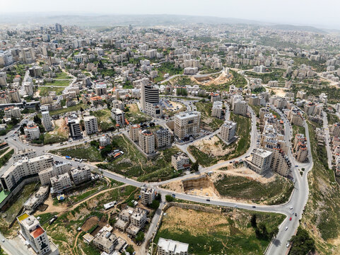 Aerial view of modern residential buildings and roads in a scenic valley, Ein Musbah, Ramallah and al-Bireh Governorate, Palestine.