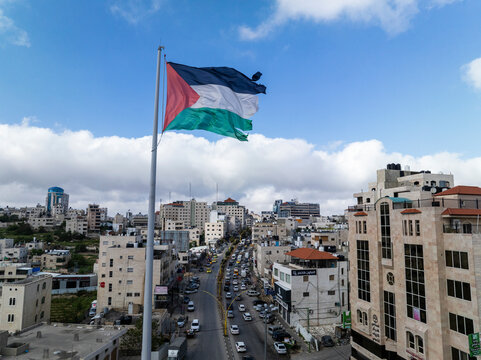 Aerial view of bustling cityscape with vibrant buildings and Palestinian flag, Hebron, Palestine.