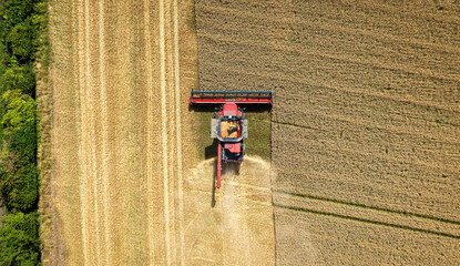 Aerial view of a green field with rows of harvested grain and a tractor, Haddington, United Kingdom.